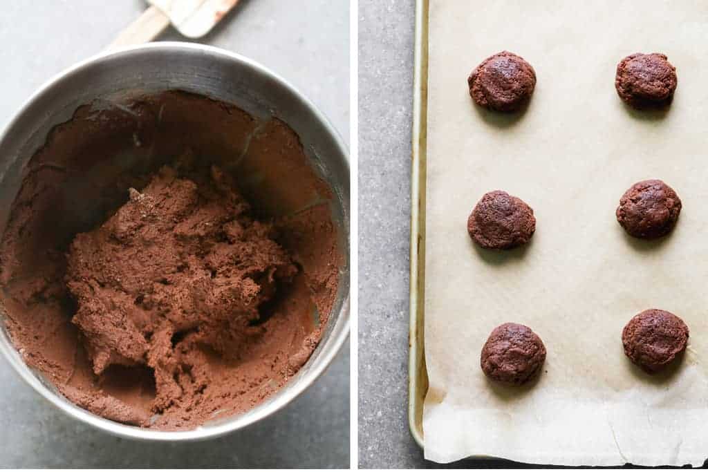 A bowl of chocolate cookie dough next to a cookie sheet with rolled cookie dough balls.