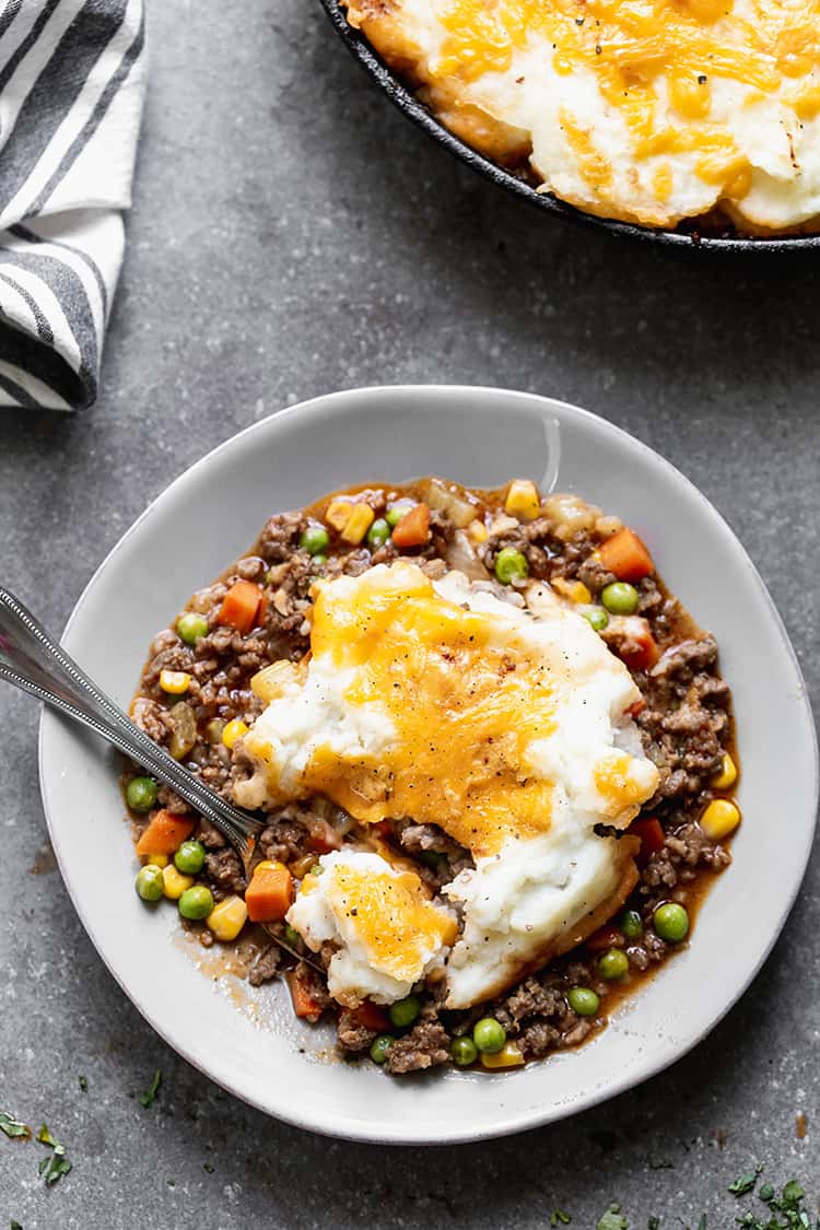 A plate with the best Cottage Pie recipe with fluffy and cheesy mashed potatoes on top.