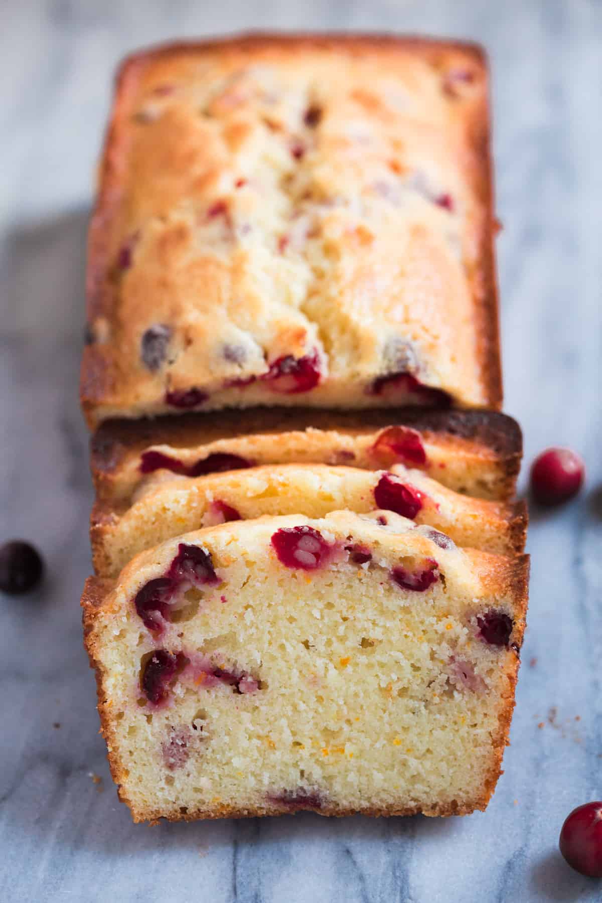 A loaf of easy Cranberry Orange Bread with half of it sliced.