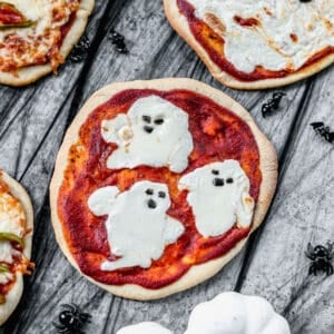 A ghost themed Halloween Pizza made with mozzarella cheese and olives for the toppings.