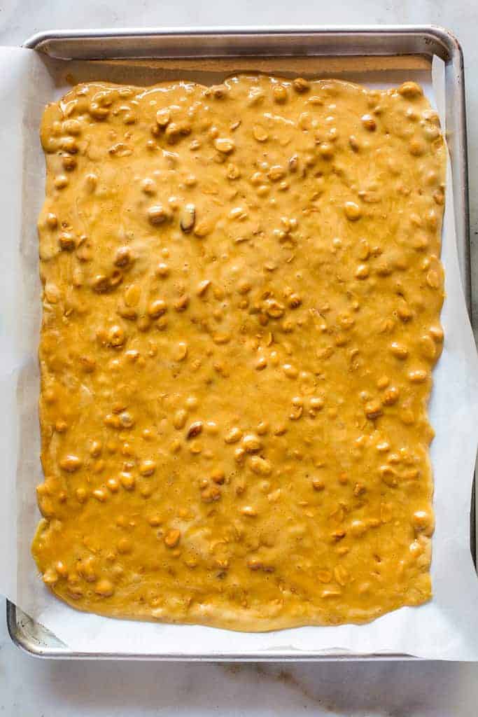 Overhead view of cooled peanut brittle in a half sheet pan.