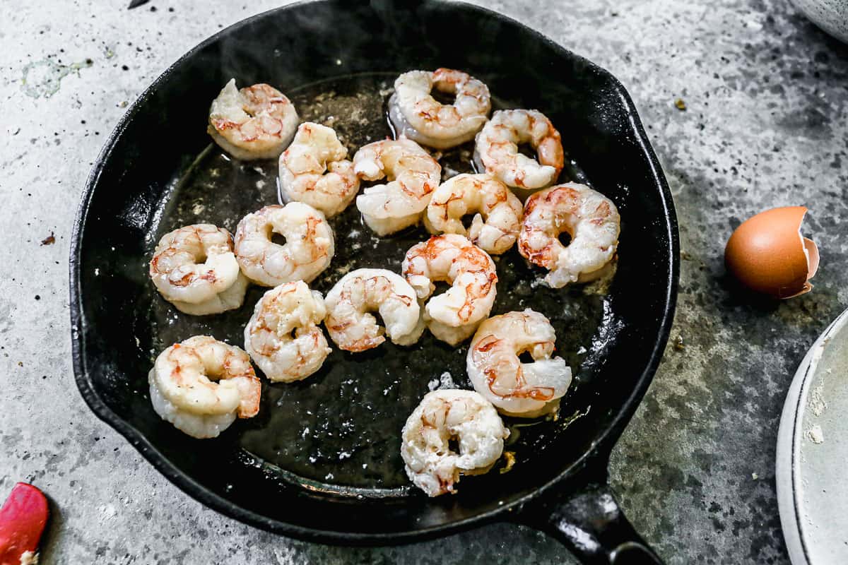 A cast iron pan with shrimp, being cooked for Shrimp and Grits.